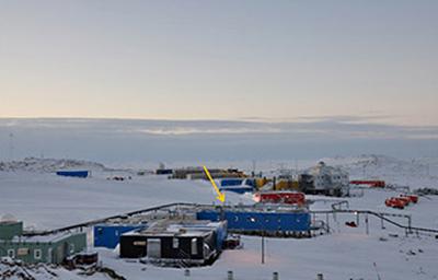 写真 南極・昭和基地。黄色の矢印で示した青い建物(観測棟)でCO2の測定を実施している(国立極地研究所提供)