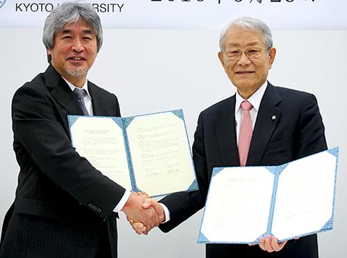 写真 協定書に調印して握手する山極寿一京都大学学長(左)と松本紘理研理事長(右)(理研提供)