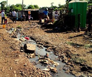 写真3 南アフリカのソウェト地区(スラム街)。ソウェト地区では5畳程のバラック小屋に8人の家族が暮らし、トイレは簡易式数個、飲み水の水道管も全コミュニティで共用、排水は地面に垂れ流しの劣悪な環境。SDGs目標1の「貧困をなくそう」について実態ベースで考える機会となった(サイトビジット訪問時)(川添菜津子撮影・文)