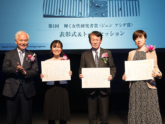 賞状を手にする3人の受賞者。左から2人目より、戎家美紀さん、九州大学総長の久保千春さん、深澤愛子さん。左は、賞を主催する科学技術振興機構(JST)の理事長濵口道成さん