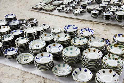 窯から取り出した完成したばかりの器（やちむん）たち。松田さんのやちむんは、素朴で落ち着いた色合いのものが多いが、鮮やかな藍や朱色の映えるダイナミックな図柄が特徴の作り手もいる。親方たちの人柄や個性が表れる
