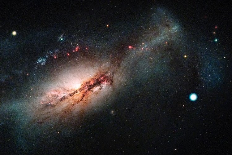 右のひときわ明るい点が、発見した電子捕獲型超新星「2018zd」。左は渦巻き銀河「NGC2146」。ラスクンブレス天文台（LCO）による2018zdの画像とハッブル宇宙望遠鏡の画像の合成（LCO、NASA、米宇宙望遠鏡科学研究所、J.デパスケール氏提供）