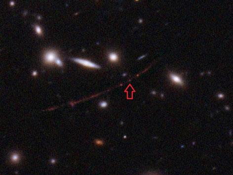矢印の先が、見つかった最遠方の星（NASA、ESAなど提供）