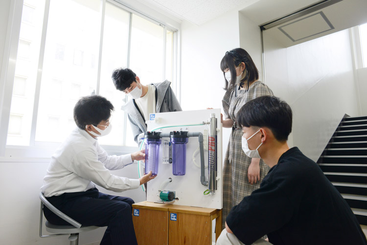 浄水装置について学生に説明する笠井さん。雨水利用に関心を持って福井工業大学に入ってくる学生もいるという