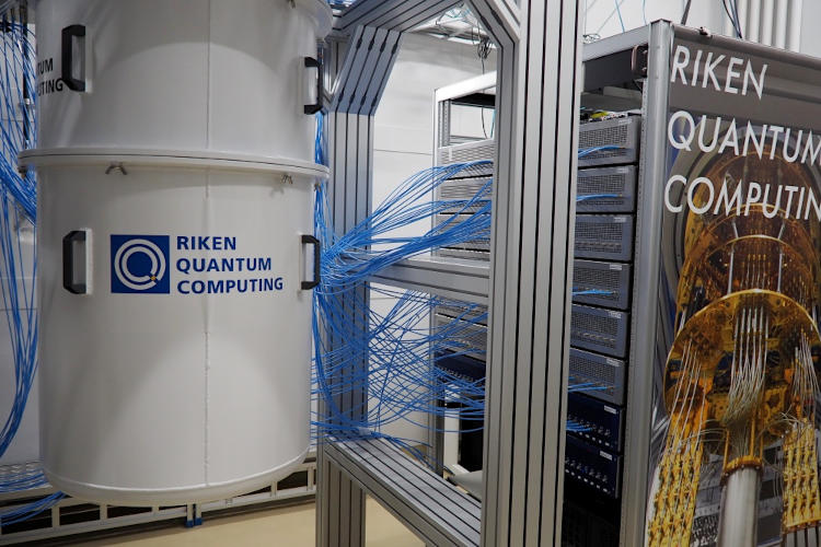 国産初の量子コンピューター。左の白い冷凍機の中に、64量子ビットの集積回路チップが収められている。多数の配線で、右の制御装置につながっている＝27日、埼玉県和光市の理化学研究所