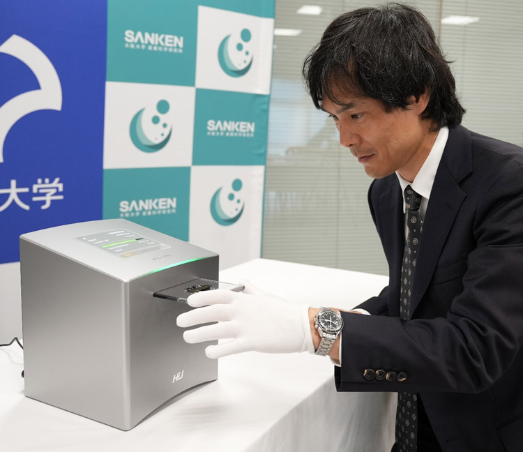 生体分子シークエンサーのプロトタイプと操作のデモンストレーションをする大阪大学の谷口正輝教授(大阪大学産業科学研究所広報室提供)