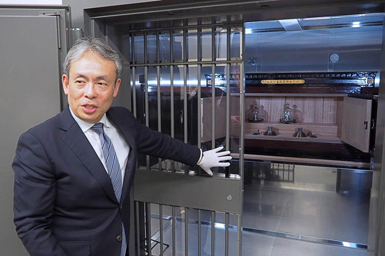 奥の金庫に厳重に保管されたキログラム原器について説明する倉本さん。金庫内の上段中央にあるのが、キログラム原器＝12日、茨城県つくば市の産業技術総合研究所