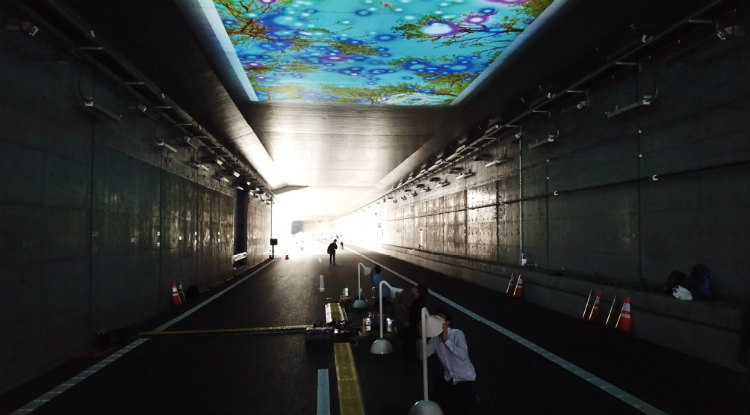 東京外かん松戸インターチェンジ開通プレイベントで披露された「未来トンネル」。トンネル内に設置されたチューブから、富士山麓の森の鳥のさえずりや風の音が聞こえ、チューブに話しかけた声は森に送られる。チューブを通した音は、トンネルの天井に映し出された映像の中に、鳥の姿や光の輪となって視覚化される。 （画像提供／清水陽子）
